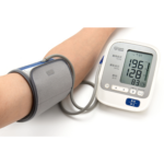 高血圧の数値が表示された血圧計と測定中の腕